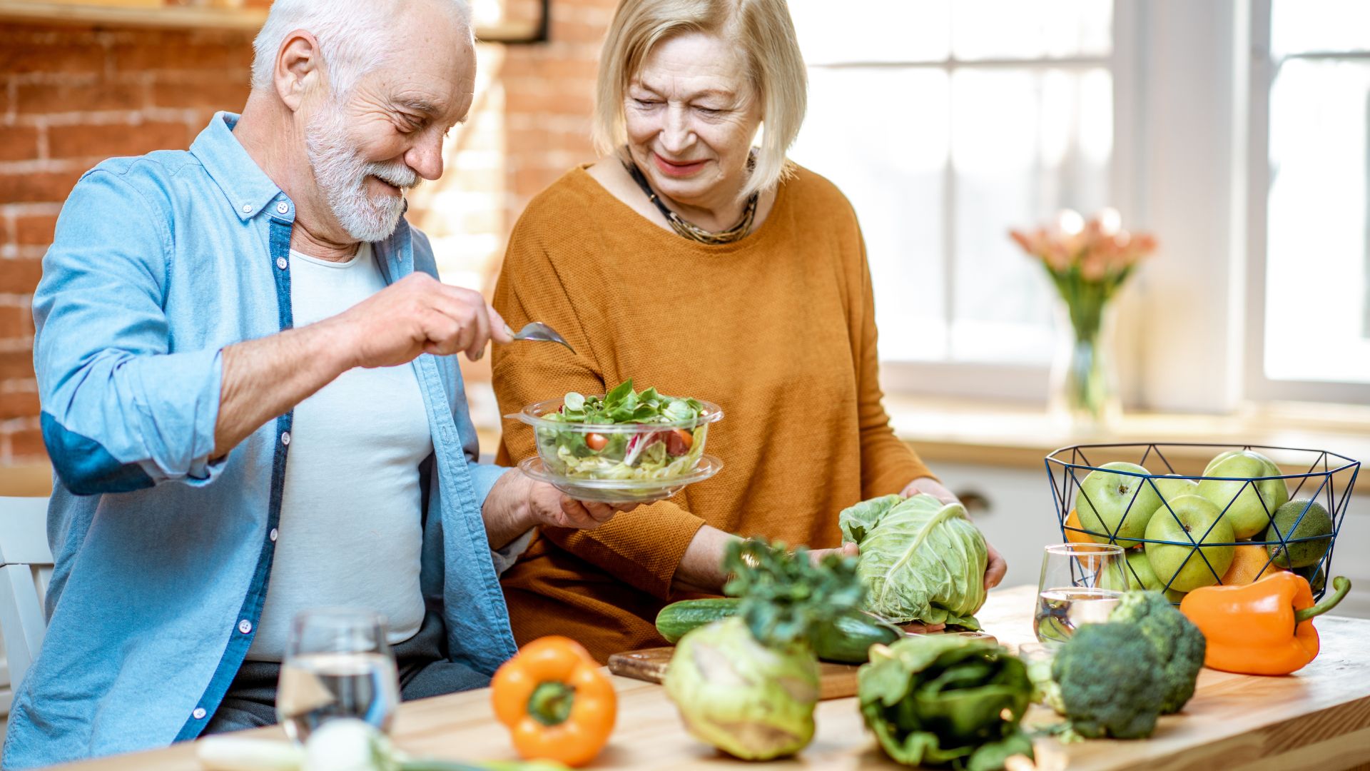 Pareja mayor comiendo ensalada en casa