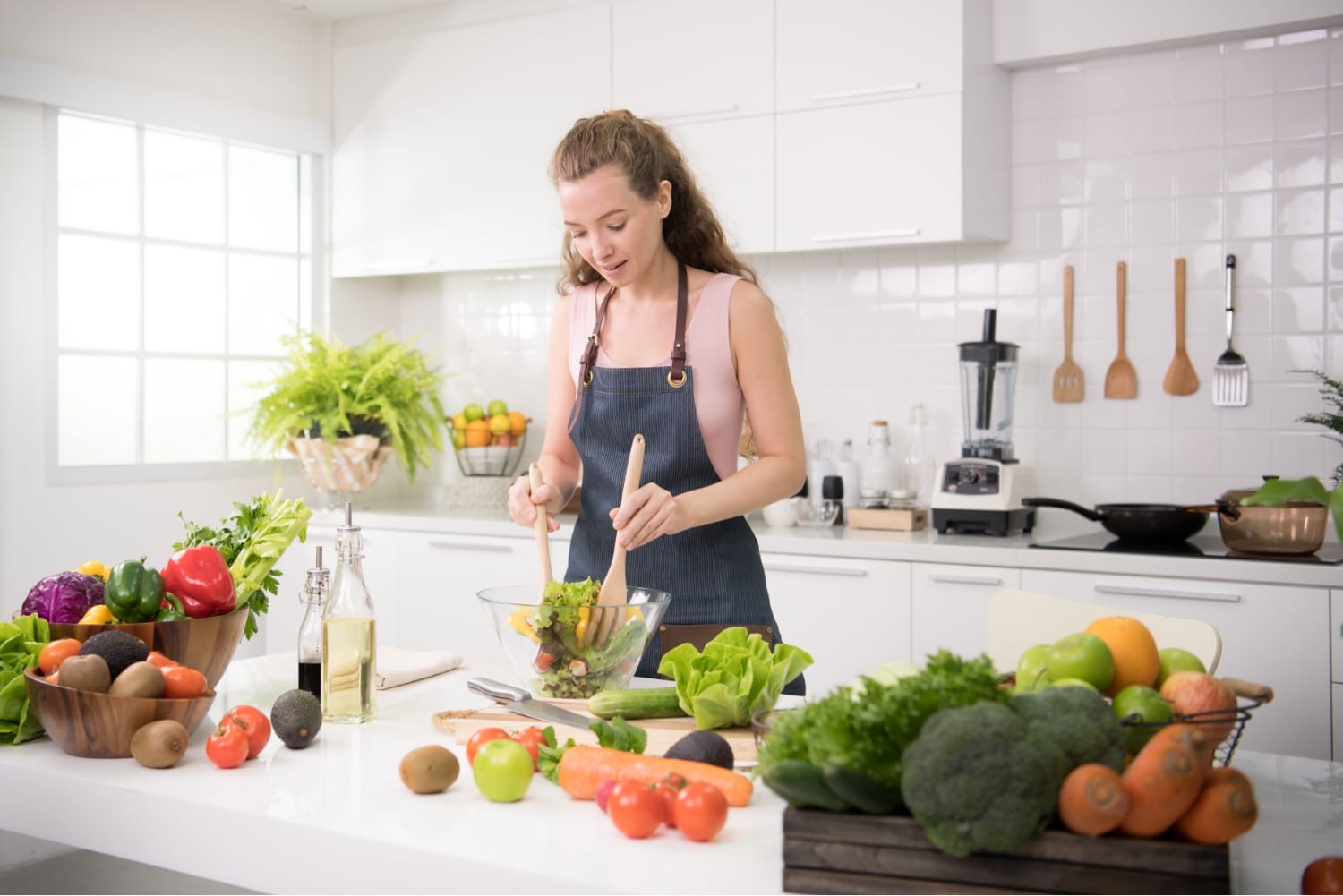 Mujer preparando una ensalada en una cocina luminosa